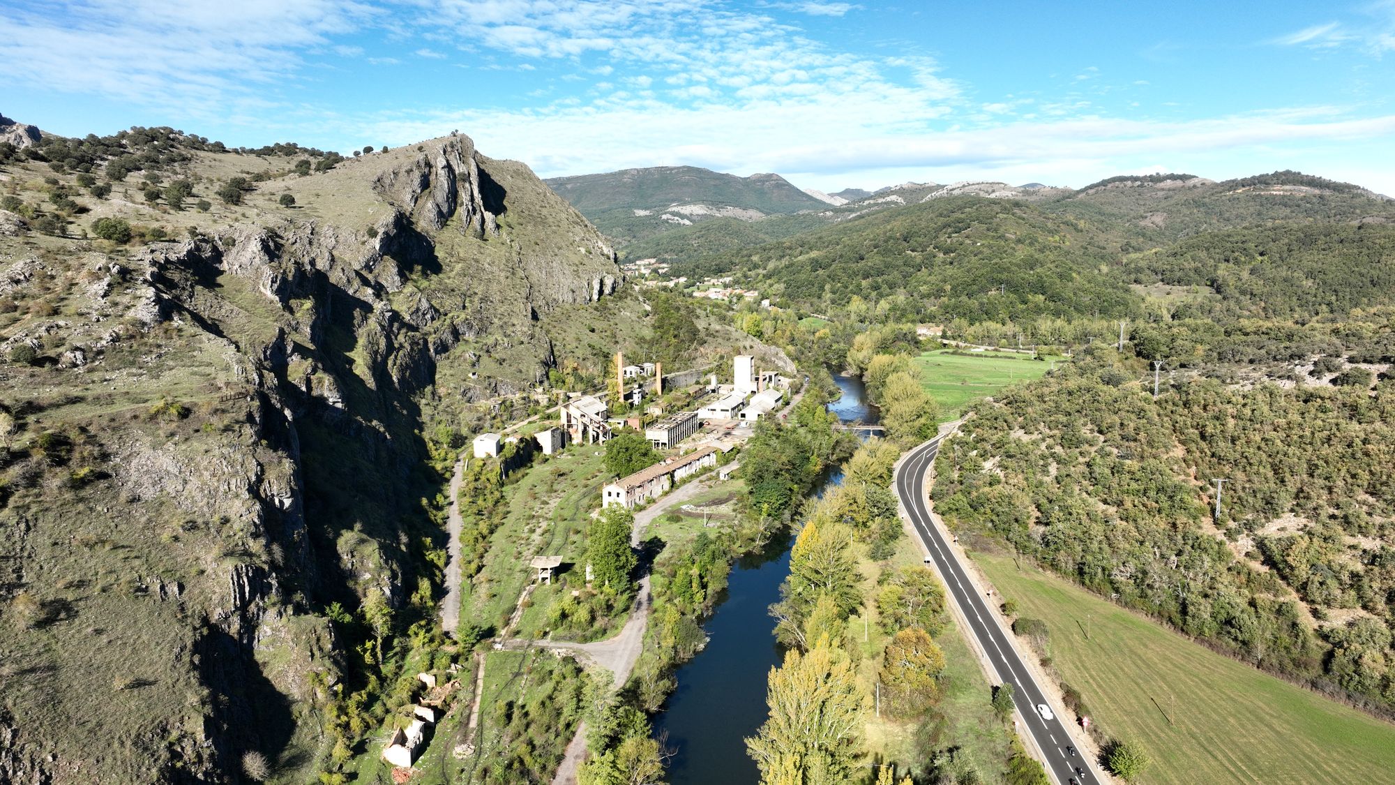 Conjunto de Vegamediana visto longitudinalmente con río contiguo, carretera en la otra margen y una pasarela de acceso al complejo.