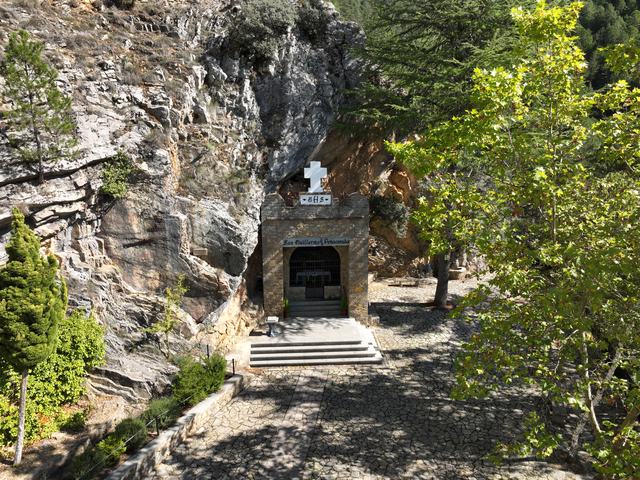Entrada de la ermita bajo la roca, cruz, reja, escalinata y atrio; rótulo San Guillermo de Peñacorada legible en ampliación.